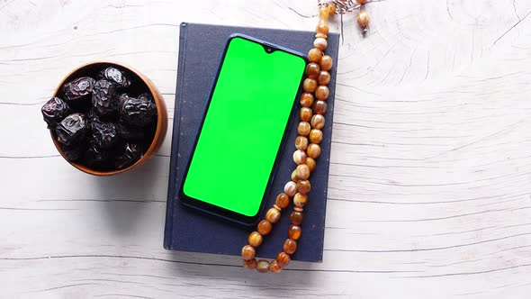 Smart Phone Holy Book Quran and Rosary on Table alt