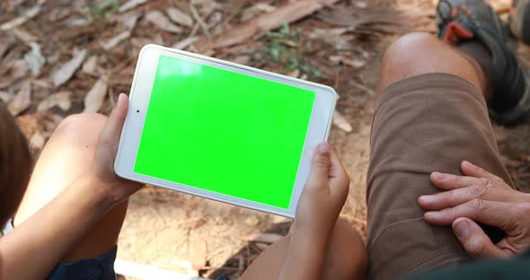 Father and son using digital tablet outside tent alt