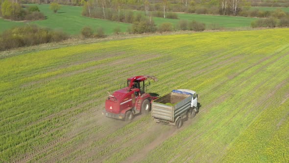 Aerial Elevated View Of Combine Harvester And Tractor Working Together In Field alt