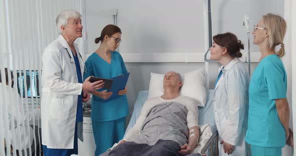 Team of Doctors and Nurses Visiting Senior Male Patient in Hospital Ward alt
