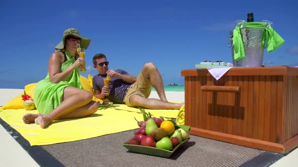 A man and woman have a picnic on a tropical island beach. alt