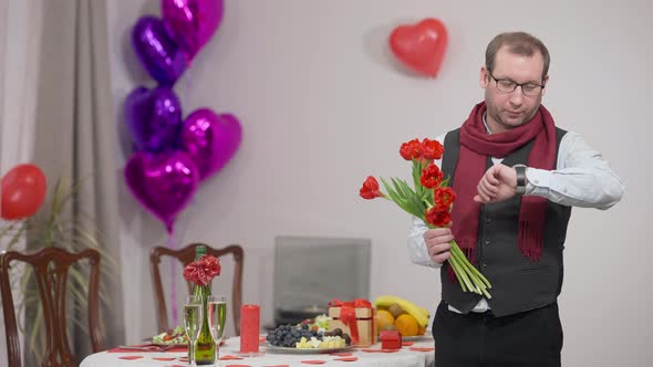 Worried Caucasian Husband Waiting for Wife on Valentine's Day with Bouquet of Tulips at Decorated alt