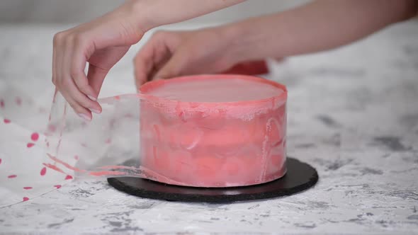 Female Pastry Chef Decorates a Raspberry Mousse Cake with Pink Chocolate