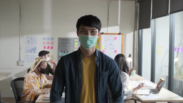Young male creative with face mask for protective and prevention covid-19 portrait in office.