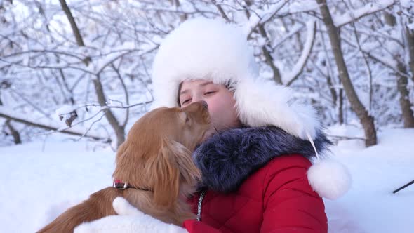 Child Plays with His Pet on Christmas Holidays in the Forest. Beautiful Girl Smiles, Caresses Her alt