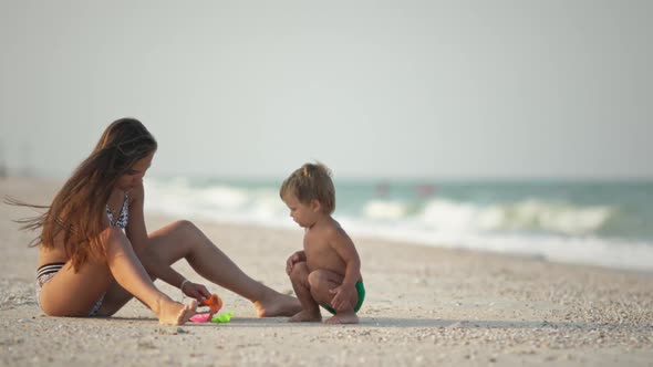 Older Sister Playing with Younger Brother Aground Near the Shore on Summer Vacation alt