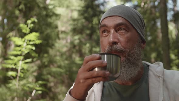 Portrait of Aged Traveler Drinking Tea Outdoors alt