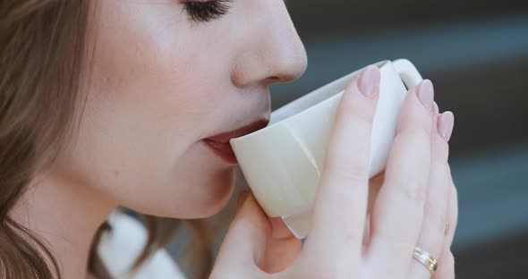 Face Portrait Closeup of Woman Drinking Coffee or Tea From White Cup