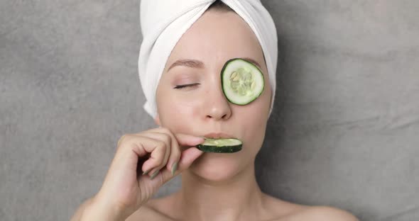 Portrait of a Young Beautiful Positive Funny Woman with a Towel on Her Head and Slices of Cucumber