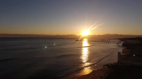 Calm Beautiful Sea Waves with Sunset Bronze Colored Wooden Piers on a Drone alt