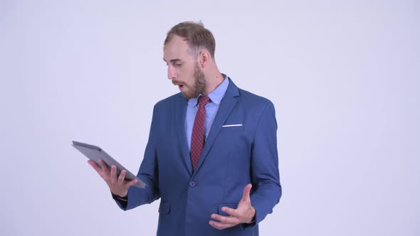 Happy Bearded Businessman Showing Digital Tablet and Looking Surprised