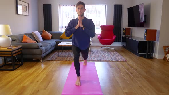 Home yoga, young male performing lunge yoga pose asana, indoors with cat