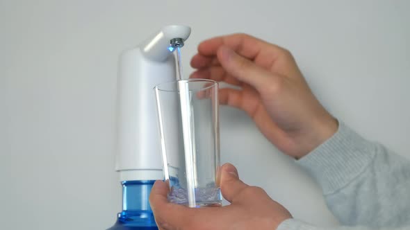 Man's Hands Pour Water Into Glass From an Automatic Water Cooler Closeup View