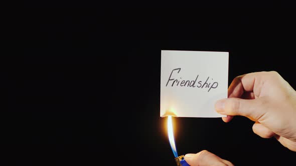 Man Burns a Paper with the Inscription Friendship alt