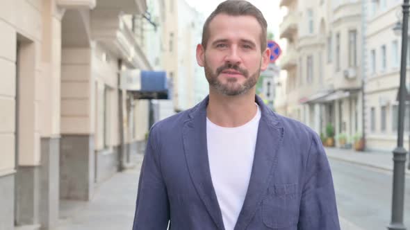 Close Up of Man Talking Towards Camera Walking Down the Street alt