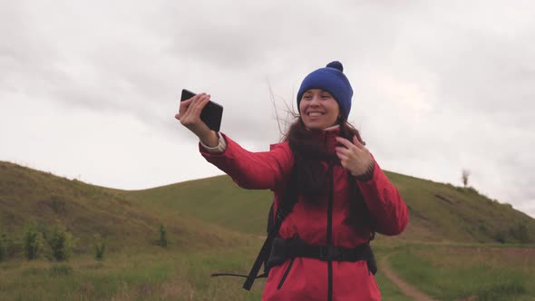 Free Young Girl Tourist Blogger Records Selfie Videos at Foot of Mountains Using a Smartphone with a alt