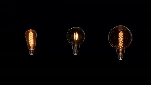 Three Edison Dirty Bulbs with Dust Inside Glass Flicker on Black Background. Amber Tungsten Color alt