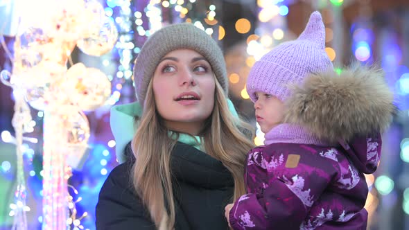 Mom and her little daughter are walking at the street Christmas market alt