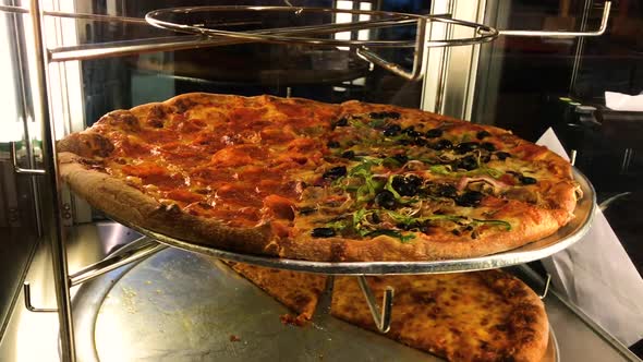Delicious Italian pizza spinning around in a glass display hot and ready to eat alt