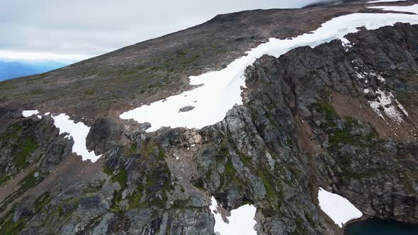 Icy mountaintops surrounding the stunning Crater Lake in British Columbia, Canada. Aerial flyover alt