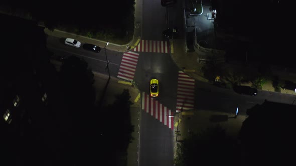 A beautiful sports car drives at night along modern city streets among skyscrapers and houses.  alt