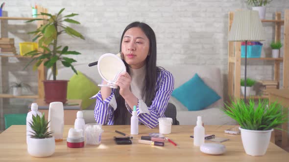 Portrait of an Asian Young Woman Using Makeup in the Living Room alt