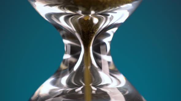 An Hourglass Made of Yellow Metal Shavings Passes Through a Funnel Symbolizing the Concept of Time alt