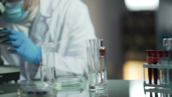 Male Lab Assistant Researching Blood Samples for Presence of Infectious Diseases alt