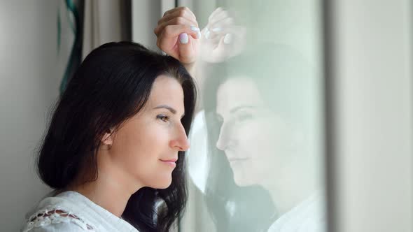 Beautiful Pensive Brunette Female in White Shirt Looking Out of Window Closeup alt