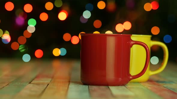 Two Bright Mugs of Hot Drink With Steam on Dark Backgroud With Colorful Lights alt
