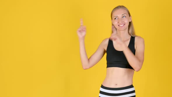 Young friendy blonde girl in sportswear smiles and shows copy space