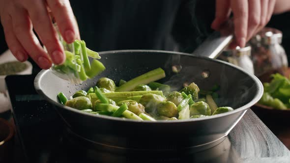Chef Frying Green Brussels Sprouts Cabbage in Pan Closeup alt