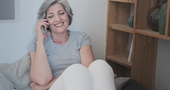 Senior Mature Old Woman Talks on the Phone with Friends or Colleagues Relaxes