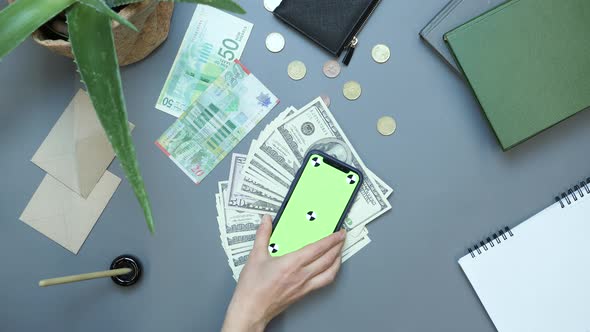 Smartphone with green screen chroma key and cash money lying on office table alt