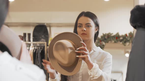 Beautiful Woman Trying on Hat at Fashion Store