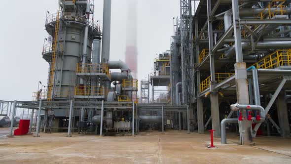 Site of oil refinery. Steel structures in foreground. Chimney in background. alt