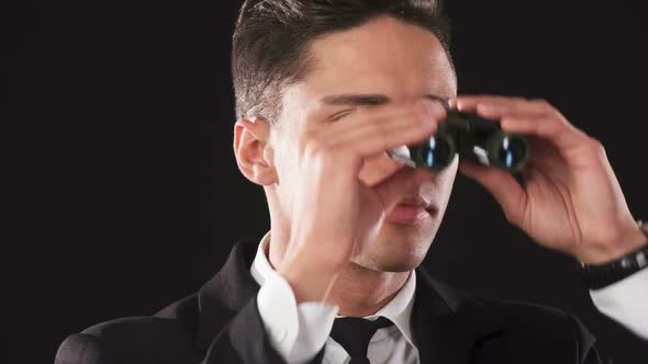Serious Man Is Looking Around in Binoculars alt