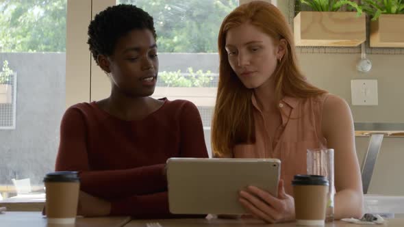 Young adult female friends hanging out in a cafe alt