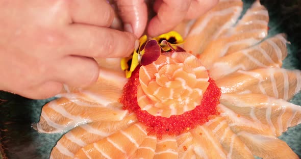 Food Plating - Chef With Putting Fresh Flowers On Top Of A Sashimi Salmon Rose. - high angle shot alt