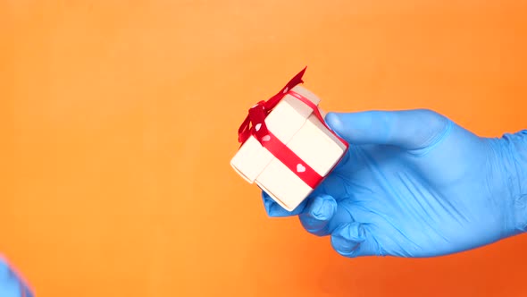 Man Gives Gift with Protective Glove. Prevention for Viruses alt