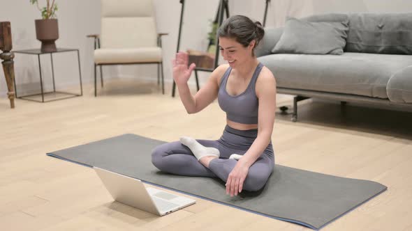 Indian Woman Talking on Video Call on Laptop on Yoga Mat alt