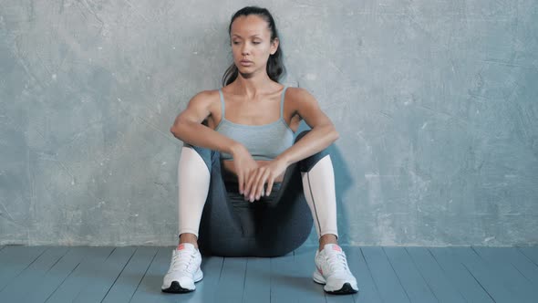 Pretty woman wearing sportswear.Beautiful girl sitting after training in studio alt
