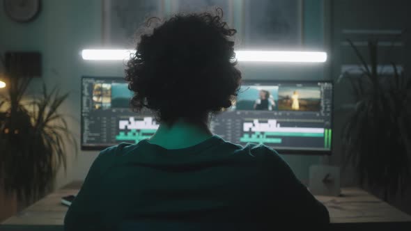 Man Using Computer to Edit Footage in Evening alt