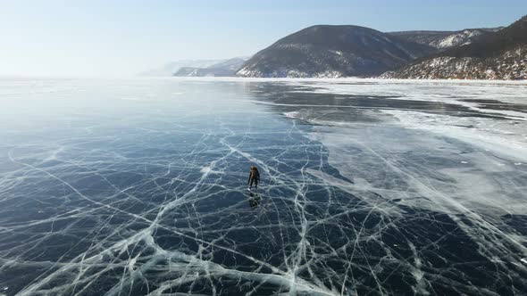 Tourist Skating on Frozen Ice Surface of Baikal Lake in Winter