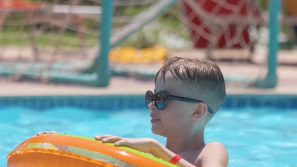 Portrait of Happy Child Boy Relaxing in Inflatable Circle in Swimming Pool on Sunny Summer Day alt