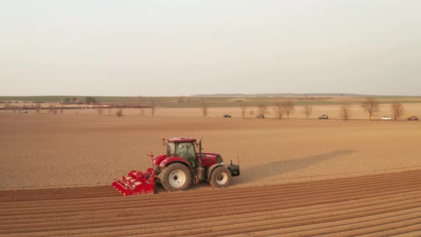 Aerial View of Red Farming Tractor Seeding Wheat at the Field alt
