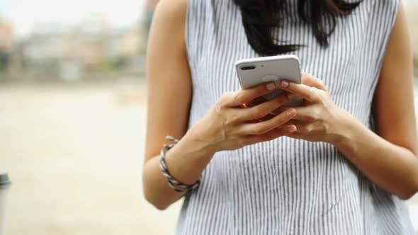 Closeup hand beautiful young Asian girl using smartphone texting messenger at outdoors.