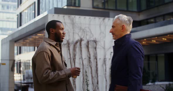 Two Men of Different Ages and Nationalities are Talking Walking in Office Center alt