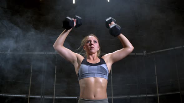 Young Blonde Fit Strong Independent Woman Working Out in a Dark Sport Gym