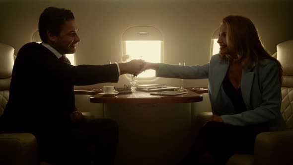 Business Partners Shaking Hands Celebrating Successful Deal on Jet Journey alt